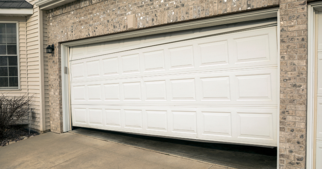 White garage door stuck; tilting off track.
